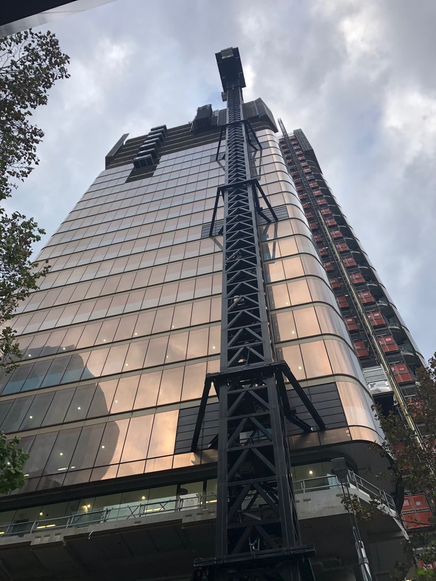 The tower under construction, looking up at the curved facade with building hoist and scaffolding still attached