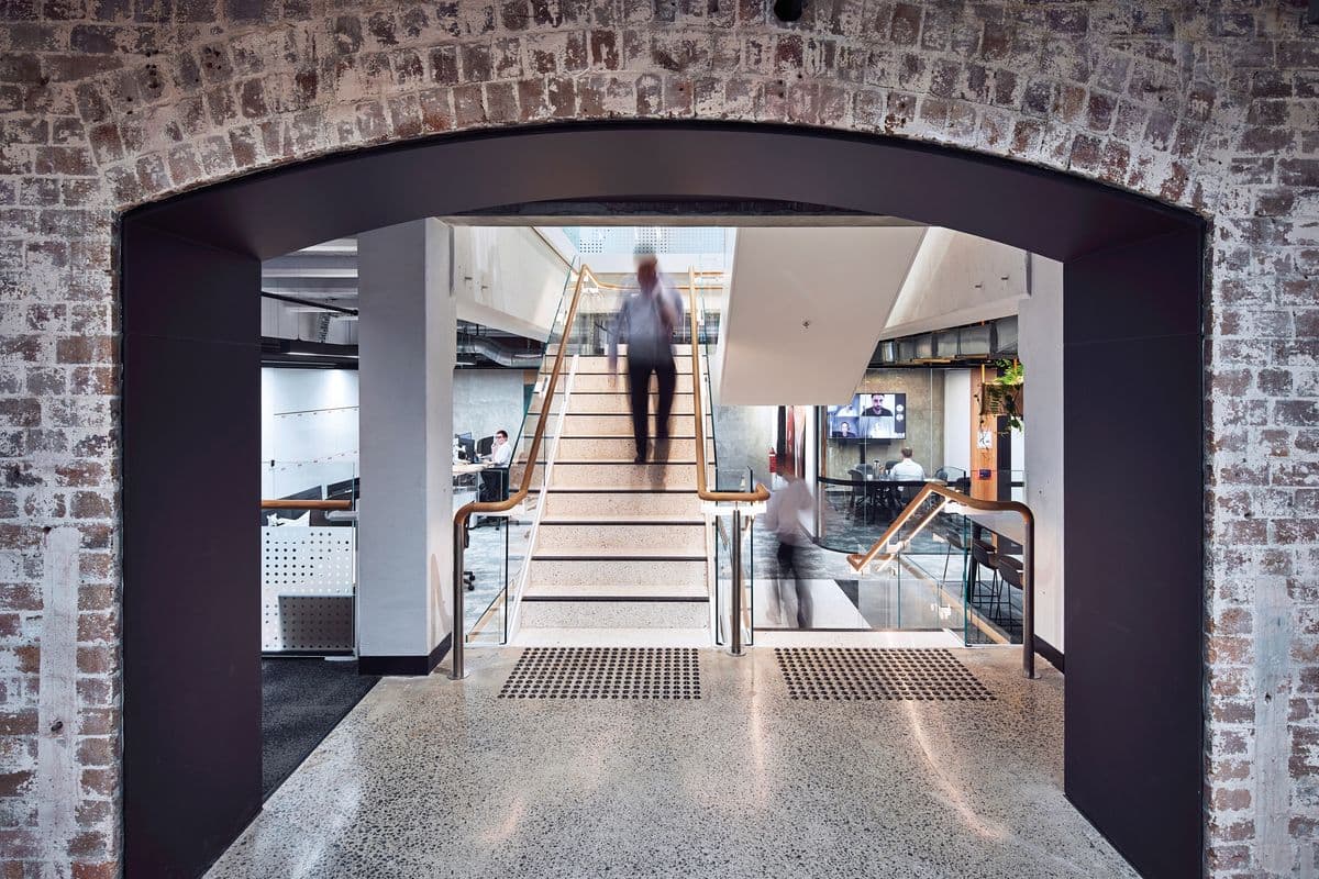 Heritage brick arch framing the contemporary office interior beyond, a junction of old and new fabric